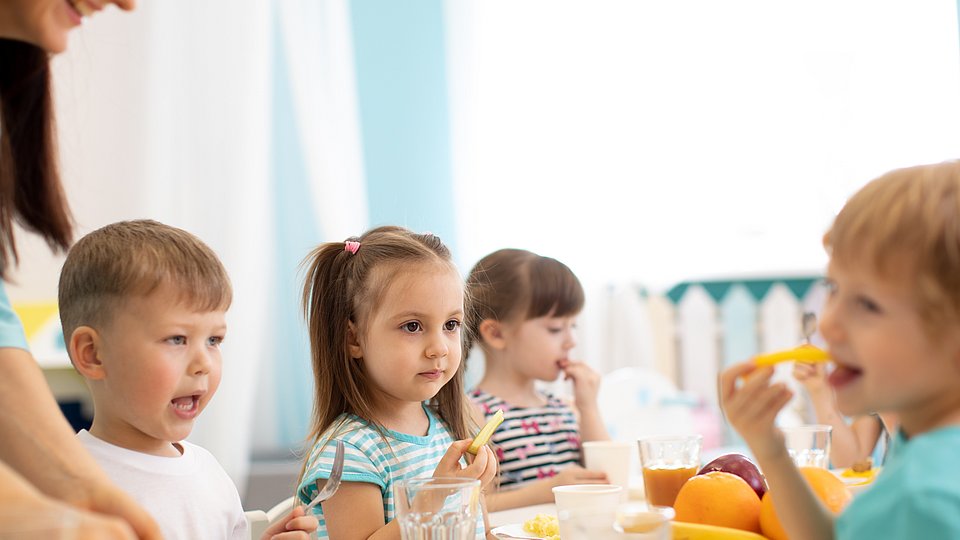 Kinder sitzen an einem Tisch und essen 