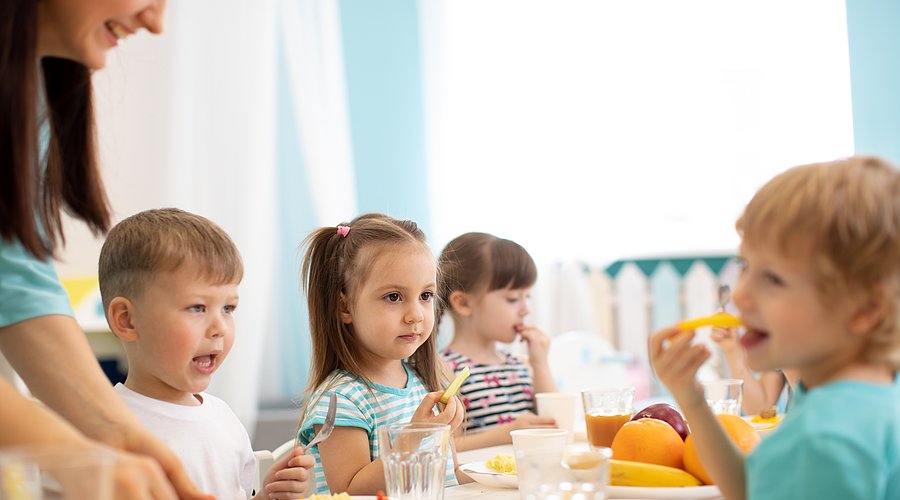 Kinder sitzen an einem Tisch und essen 