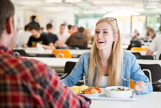 Zwei ältere Schüler sitzen gut gelaunt in der Mensa und essen Mittag 