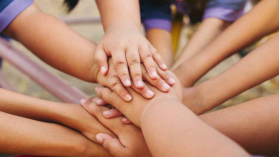 Viele Kinderhände im Kreis übereinander gelegt.