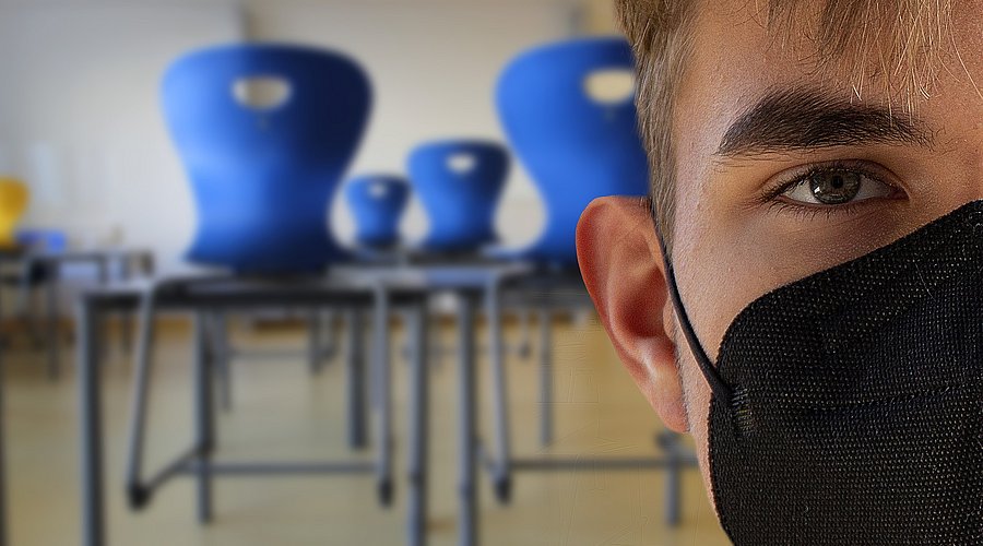 Jugendlicher Schüler mit Maske im Klassenraum