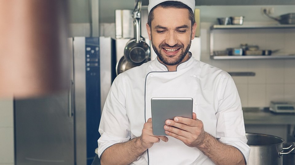 Koch guckt im Tablet nach