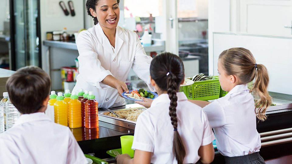 Kinder erhalten in der Mensa ihr Essen