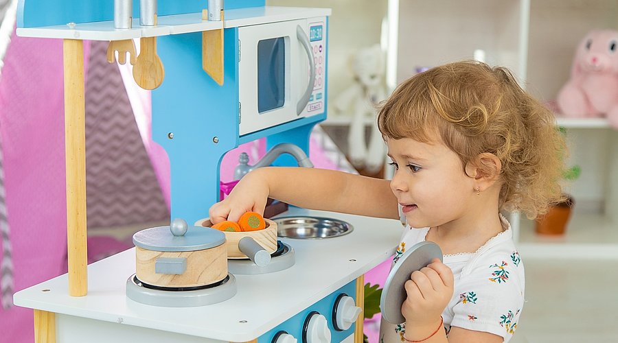 Kita-Kind kocht am Spielzeugherd.