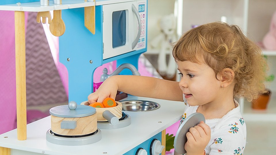 Kita-Kind kocht am Spielzeugherd.