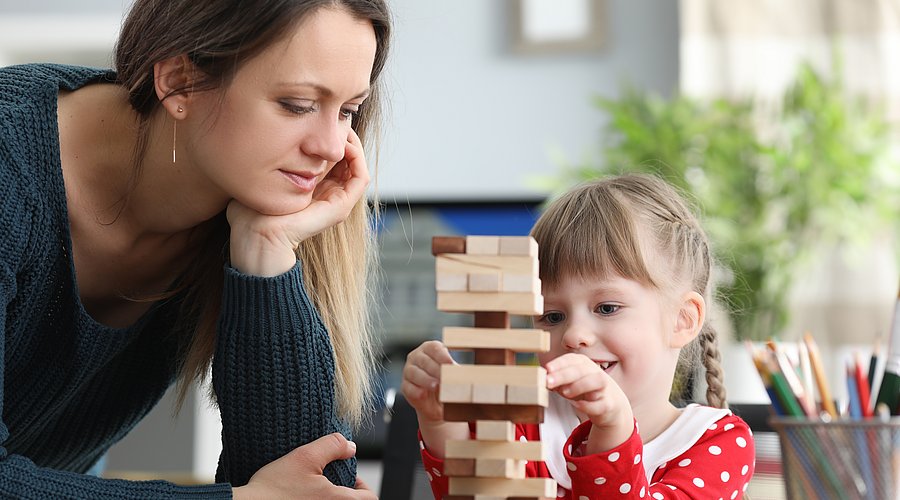 Kind und Frau bauen einen Holzspiel-Turm.