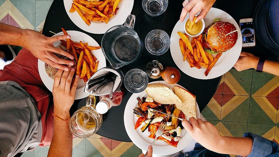 Vier Jugendliche sitzen an einem Tisch und essen Fast Food