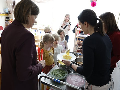 Die Parlamentarische Staatssekretärin beim Bundesminister für Ernährung und Landwirtschaft, Dr. Manuela Rottmann mit Anna Heyer-Stuffer, Staatssekretärin im Ministerium für Soziales, Gesundheit, Integration und Verbraucherschutz des Landes Brandenburg (2 v. links) und der Parlamentarischen Staatssekretärin bei der Bundesministerin für Familie, Senioren, Frauen und Jugend, Ekin Deligöz (rechts) beim Austeilen von Essen in der  Kita Klein & Groß in Königs Wusterhausen (Brandenburg).  