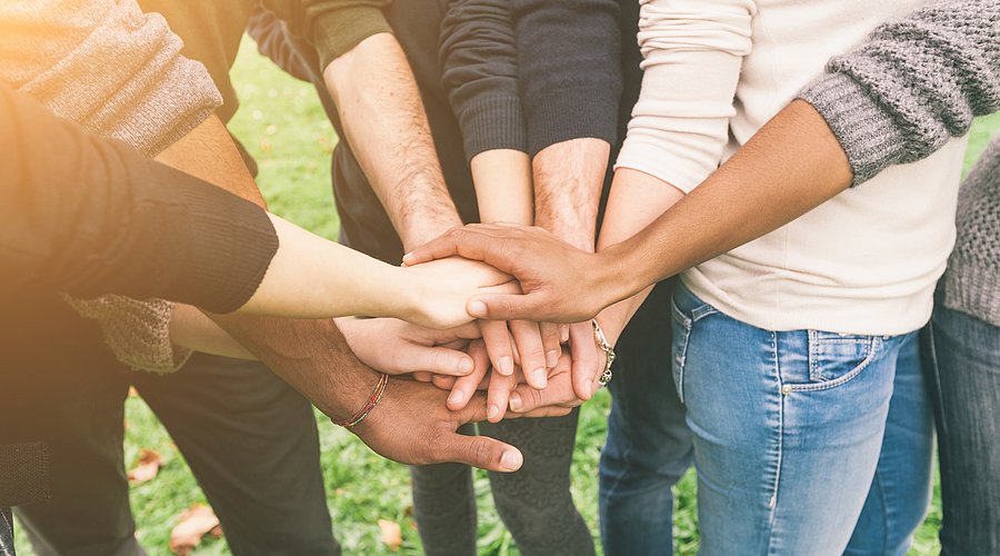 Gruppe von Menschen legen Hände in der Mitte zusammen