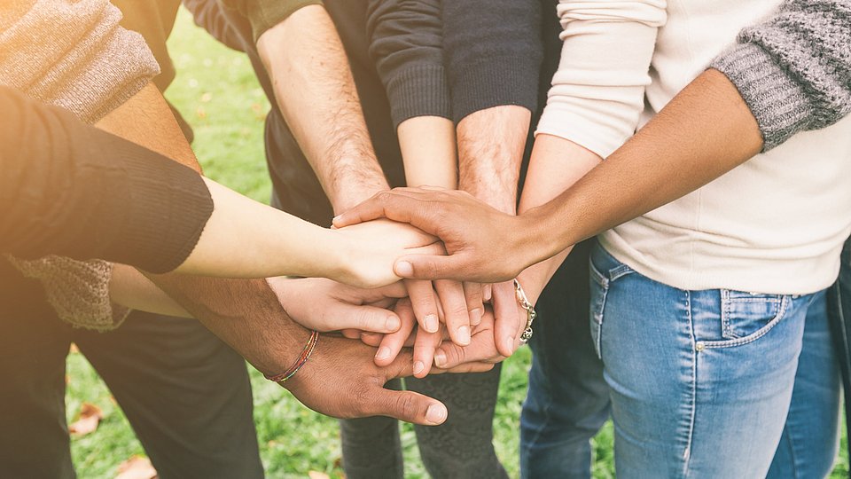 Gruppe von Menschen legen Hände in der Mitte zusammen