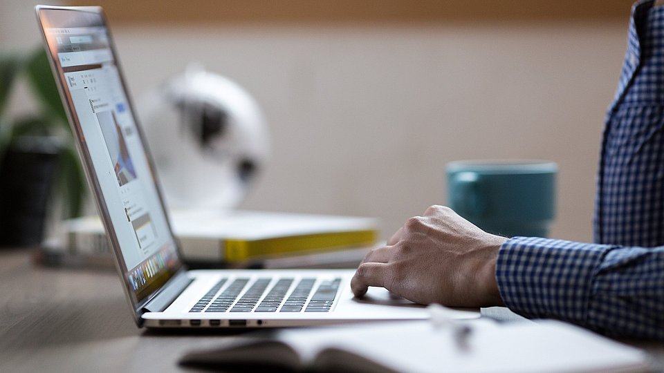 Ein Mann sitzt vor dem Laptop. 