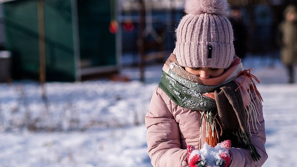 Mädchen spielt im Schnee. 