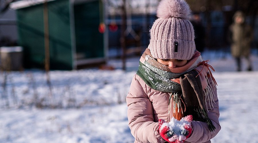 Mädchen spielt im Schnee. 