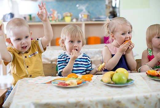 Kitakinder essen gemeinsam an einem Tisch 