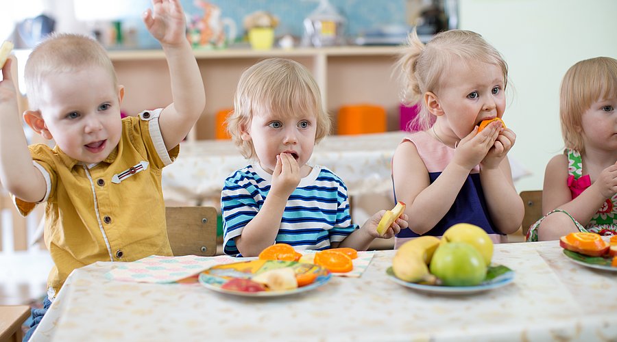 Kitakinder essen gemeinsam an einem Tisch 