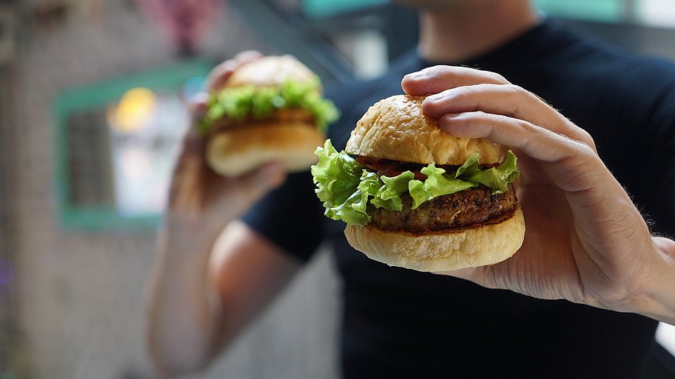 Junge hält in jeder Hand zwei kleine Burger