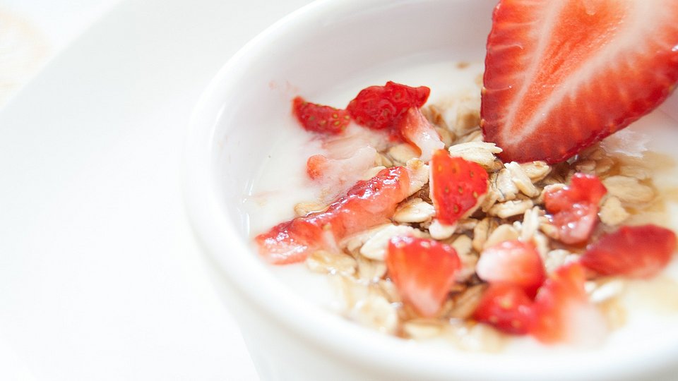 Müsli-Schale mit Haferflocken, Milch und frischen Erdbeeren