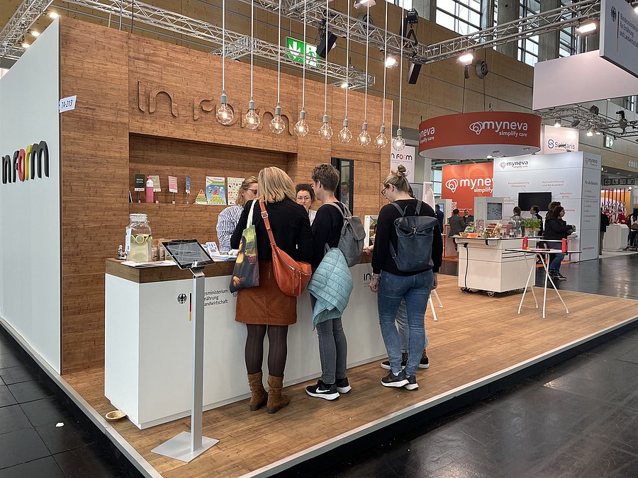 Am IN FORM-Stand auf der Messe ConSozial in Nürnberg 2023 beraten Mitarbeiterinnen des Bundeszentrums für Ernährung interessierte Messebesucherinnen. 