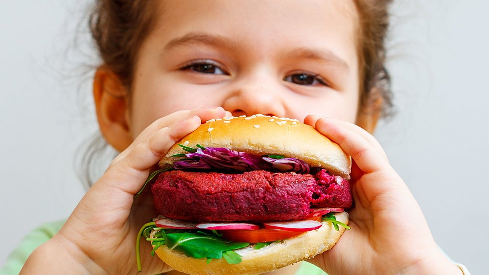 Kita-Kind beißt in Plant-based-Burger.