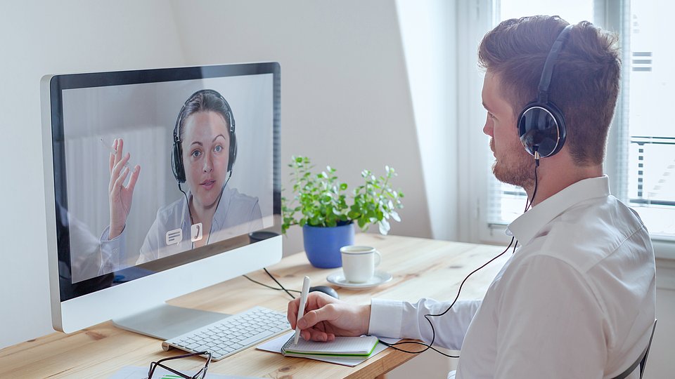 Mann sitzt am Schreibtisch im Büro und nimmt an einem Webseminar teil.