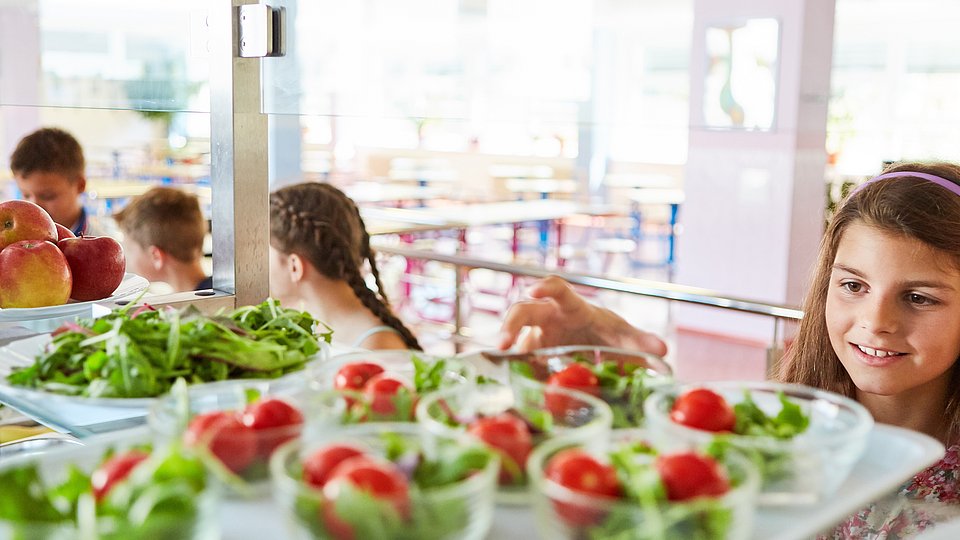 Jugendliche Schülerin bedient sich in der Mensa am Salatbuffet.