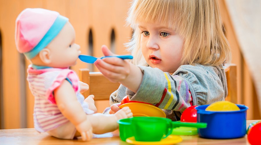 Ein Mädchen füttert seine Puppe