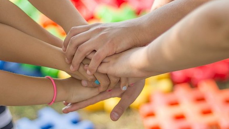 Kinder halten ihre Hände zum Zeichen des Miteinanders übereinander