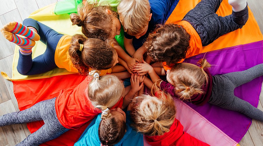 Kita-Kinder liegen bäuchlings im Kreis.